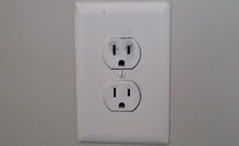 Residential electrical outlet showing slight discoloration around receptacle slots, an early warning sign of heat stress or loose connection